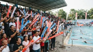 Balon tepuk berwarna merah dan biru digunakan penonton untuk memberikan semangat pada perlombaan renang.