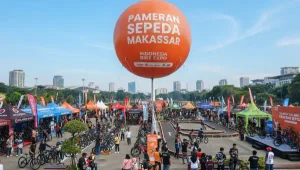 Balon udara Makassar berwarna oranye menjadi penanda visual pada acara pameran sepeda di area terbuka.